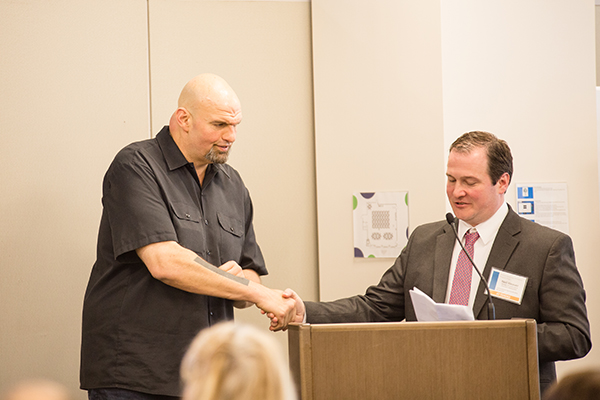 Lt. Gov. Fetterman shaking hands with Neil Weaver at the podium.