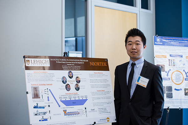 Student in a suit standing with his poster.