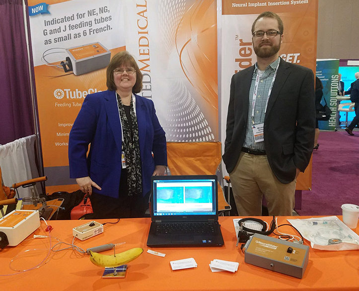 Two people standing in front of a table at a conference