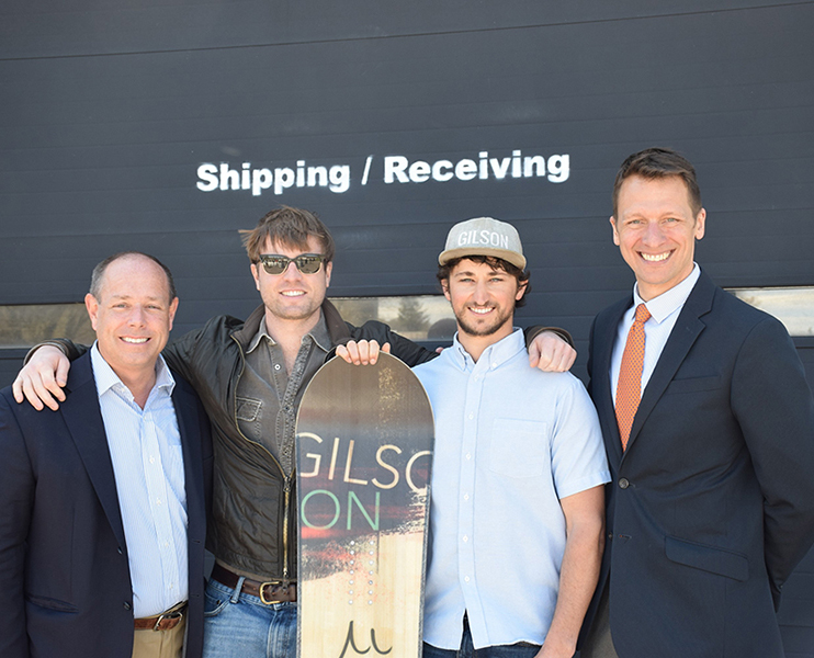 Four men standing with a snowboard